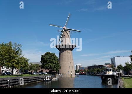 Hohe Windmühle in der Nähe von Wasserkanal und Gasse in Schiedam, Holland Stockfoto