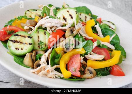 Warmer Hähnchensalat mit Spinat, Tomatenscheiben, Paprika, gegrillten Zucchini und Champignons, alles Stockfoto