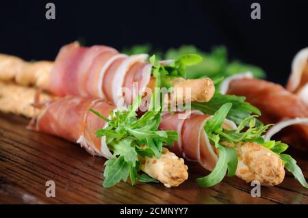 Grissini - Brotscheiben mit Parmesan, eingewickelt mit einem Stück Prosciutto und Rucola. Italienische DIS Stockfoto