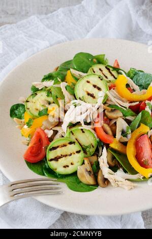 Warmer Hähnchensalat mit Spinat, Tomatenscheiben, Paprika, gegrillten Zucchini und Champignons, alles Stockfoto