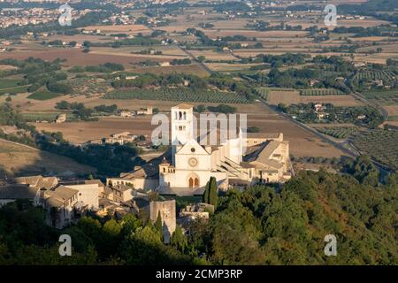 Basilika des Heiligen Franziskus von Assisi, Basilika Papale di San Francesco, mit Statue bei Sonnenaufgang in Assisi, Umbrien, Italien Stockfoto