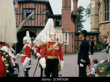 Sechziger Jahre, historisch, außerhalb Windsor Castle, Queens Guards tragen ihre roten Kleid Tuniken im zeremoniellen Dienst, mit einem britischen Polizisten auch in Anwesenheit. Seit 1660 gehört das Privileg, den Souverän zu bewachen, zu den Haushaltstruppen oder "The Guards", die aus fünf Infanterieregimenten - den Grenadier, Colddampf, Schotten, Irischen und Walisischen Garden - und zwei Regimenten der Household Cavalry - den Life Giards und den Blues und Royals bestehen. Stockfoto