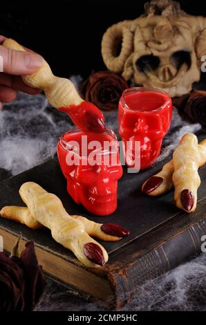 Tauchen Sie knusprige Shortbread-Kekse in Form von Hexenfingern In heißer Schokolade Red Velvet.Dies ist Jus Stockfoto