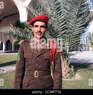 1960er, Saudi-Arabien, Dhahran, Saudi National Guard oder Police Sergeant stehen für ein Bild in seiner braunen oder khakifarbenen Uniform und roten Baskenmütze, eine Farbe von britischen und US-Armee Modelle beeinflusst. 2015 wurde die traditionelle kahki durch neue schwarze Uniformen ersetzt. Stockfoto