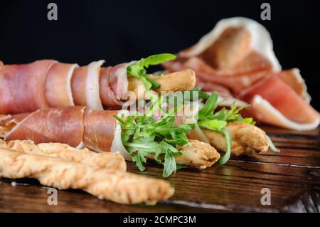 Grissini - Brotscheiben mit Parmesan, eingewickelt mit einem Stück Prosciutto und Rucola. Italienische DIS Stockfoto