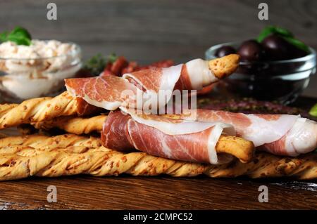 Gericht für Antipasti-Snacks mit Salami, Brotscheiben (Grissini), eingewickelt mit Prosciutto-Oliven und Lauch Stockfoto