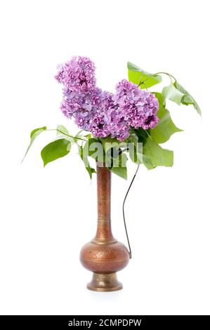 Ein Bouquet von rosa Flieder in einem orientalischen Kupferkrug auf einem sauberen weißen Hintergrund. Isoliert. Stockfoto