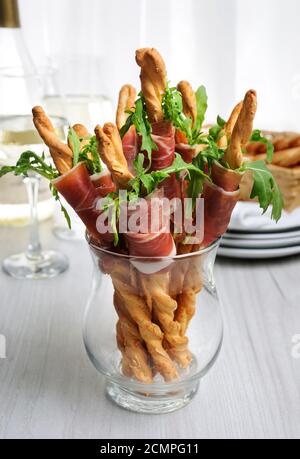 Grissini - Brotscheiben mit Parmesan, eingewickelt mit einem Stück Prosciutto und Rucola. Italienisches Gericht Stockfoto