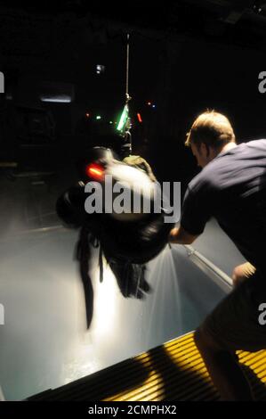 Navy Diver 1. Klasse ein Instruktor am Aviation Survival Training Kurs, wirft einen Schüler auf einem Hebezeug Stockfoto