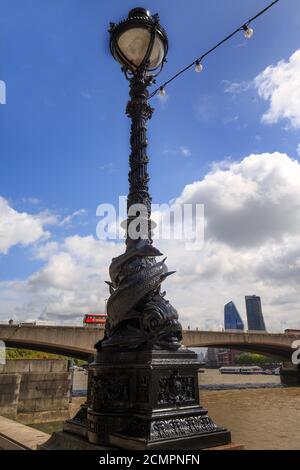 Old Victorian Dolphin Lamp am Ufer der Themse in London, mit einem Bus über die Waterloo Bridge im Hintergrund Stockfoto