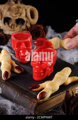 Tauchen Sie knusprige Shortbread-Kekse in Form von Hexenfingern In heißer Schokolade Red Velvet.Dies ist Jus Stockfoto