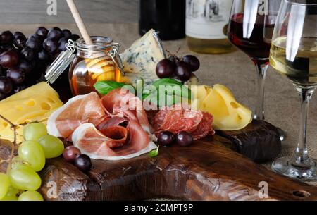 Antipasti-Catering-Platte mit ruckigem Speck, Schinken, Salami, Käse und Trauben auf einem hölzernen b Stockfoto