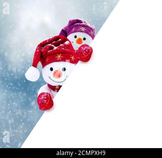 Zwei kleine Schneemänner das Mädchen und der Junge in Mützen und Schals auf Schnee im Winter. Festliche Hintergrund mit einem lustigen Schneemann. Weihnachtskarte, kopieren. Stockfoto