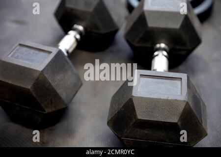 Kurzhanteln oder Gewichte auf schwarzen Gummifußböden im Fitnessstudio Konzept für das Training Stockfoto