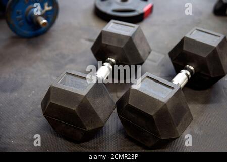 Kurzhanteln oder Gewichte auf schwarzen Gummifußböden im Fitnessstudio Konzept für das Training Stockfoto