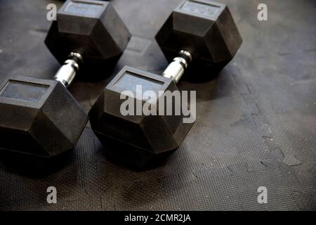 Kurzhanteln oder Gewichte auf schwarzen Gummifußböden im Fitnessstudio Konzept für das Training Stockfoto