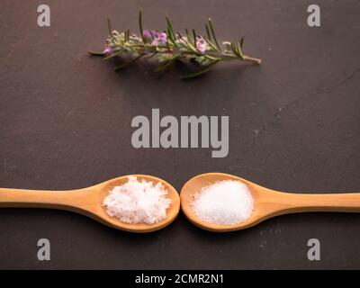 Holzlöffel mit gemeinsamen marine Salz und Salz Blume Flocken auf einer Schiefertafel Platte Stockfoto