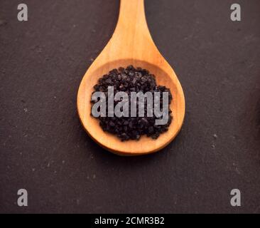 Löffel aus Holz mit Hawaii Salz schwarz auf einer Schiefertafel Platte Stockfoto