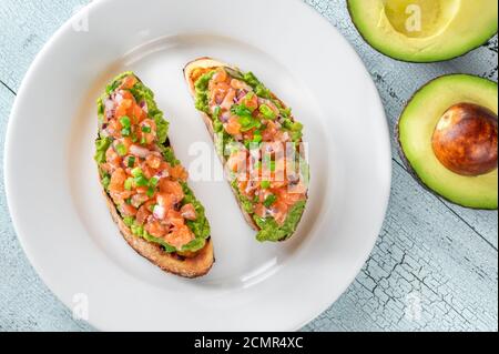 Zwei Guacamole und Lachs Toasts auf weißem Teller Stockfoto