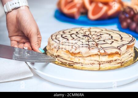 Frauenhände schneiden ganze esterhazy Torte Kuchen mit Messer. Authentisches Rezept, ungarisches und österreichisches Dessert, Blick von oben, clos Stockfoto