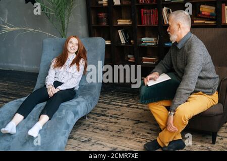 Seitenansicht einer depressiven rothaarigen jungen Frau, die über Probleme im bequemen Sessel spricht. Stockfoto