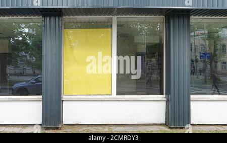 Das Leben auf der Straße spiegelt sich in den Glasfenstern eines geschlossenen Konkursladens wider. Stockfoto