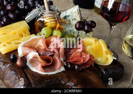 Antipasti-Catering-Platte mit ruckigem Speck, Schinken, Salami, Käse und Trauben auf einem hölzernen b Stockfoto