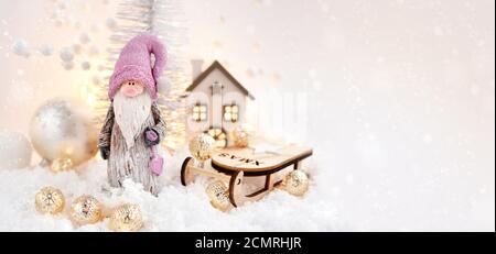 Weihnachtskomposition. Der Gnom und Schlitten mit festlichen Dekorationen оn den Schnee. Grußkarte zu Weihnachten oder Neujahr. Platz für Ihren Text Stockfoto