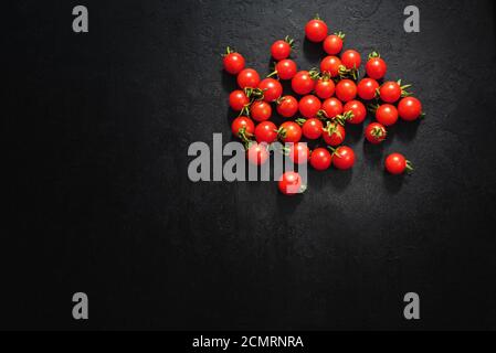 Reife Kirschtomaten auf schwarzem Hintergrund. Draufsicht. Speicherplatz kopieren Stockfoto