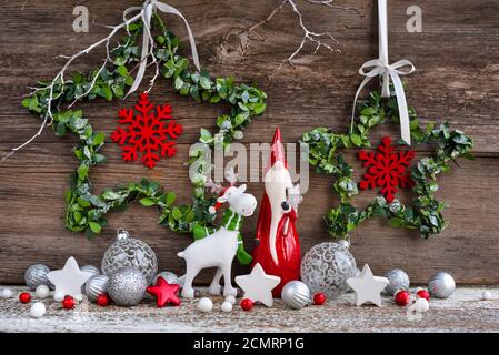 Weihnachtskomposition mit Gnom, Elchfigur und festlichen Dekorationen auf Holzhintergrund. Grußkarte zu Weihnachten oder Neujahr. Stockfoto