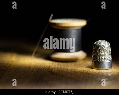 Vintage-Nimble und Holz-Baumwoll-Rolle mit Nadel und schwarz Gewinde Stockfoto