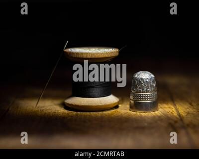 Vintage-Nimble und Holz-Baumwoll-Rolle mit Nadel und schwarz Gewinde Stockfoto