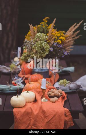 Herbst themed Urlaub Tisch Einstellung Arrangement für eine saisonale Party, Gläser, Kürbisse, Kerzen, Feldblumen Stockfoto