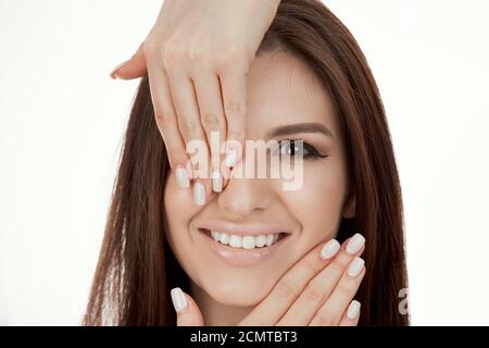 Schöne Modell Mädchen, Frau Gesicht mit Händen, die Auge um Gesicht mit einem weißen beige Maniküre Nageldesign isoliert auf reinem weißen Hintergrund. Fashio Stockfoto