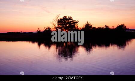 Sonnenuntergang über Assateague Island mit Silhoutte von Sümpfen, Wasser, hohem Gras und Bäumen. Stockfoto