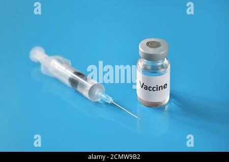 Medizinisches Fläschchen mit Impfstoff und einer Einwegspritze auf blauem Hintergrund. Geringe Schärfentiefe, selektiver Fokus. Gesundheitskonzept. Stockfoto