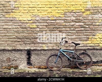 Alte rostige Oldtimer Fahrrad gegen eine Mauer gelehnt Stockfoto