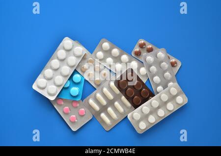 Heap verschiedene Pillen in Blisterpackung auf einem blauen Hintergrund close-up, flach legen. Konzept der Gesundheitsversorgung. Stockfoto