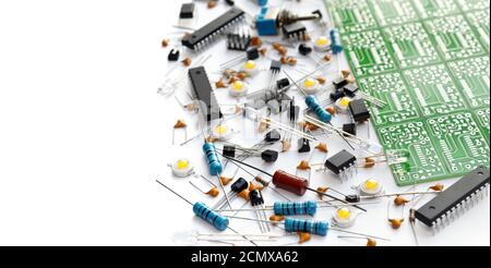 Verschiedene elektronische Komponenten in der Nähe von grünen elektronischen Leiterplatte auf weißem Hintergrund mit Kopierraum angeordnet. Nahaufnahme, selektiver Fokus Stockfoto