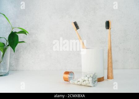 Keine Abfallprodukte im Bad. Bambus-Zahnbürsten in Recycling-Material Halter, natürliche Mundspültabs und frische grüne Pflanzen in Glas. Mundpflege Stockfoto