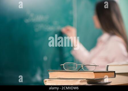 Junge lächelnde Lehrerin im Klassenzimmer Armaturenbrett mit Kreide Stockfoto