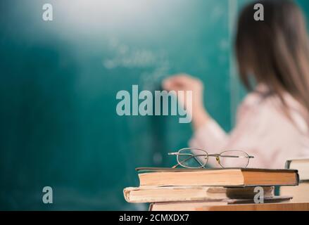 Junge lächelnde Lehrerin im Klassenzimmer Armaturenbrett mit Kreide Stockfoto