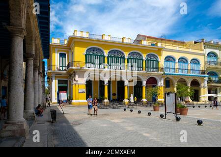 Touristen und Einheimische an einem bunten Platz in der Altstadt von Havanna Stockfoto