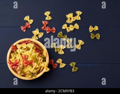 Rohe Pasta in Form von Bögen in einem hölzernen Runder Teller und weiße Textilserviette Stockfoto