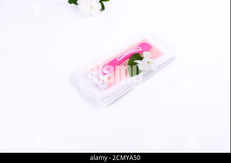 Eine Reihe verschiedener Möglichkeiten zum Epilieren auf einem farbigen Hintergrund. Entfernung von unerwünschten Haaren. Körperpflegeprodukte, Handtücher, Jasminblüten, Wachsstreifen, Rasiermesser. Minimalismus, Draufsicht. Flatlay Stockfoto