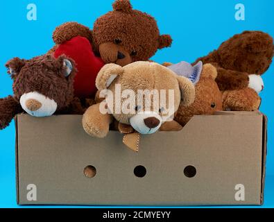 Braune Pappschachtel mit verschiedenen Teddybären, blauer Hintergrund Stockfoto
