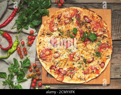 Gebackene runde Pizza mit geräucherten Würstchen, Pilzen, Tomaten Stockfoto