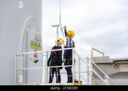 Asiatische Mann und Frau Inspektionsingenieure Vorbereitung und Fortschrittskontrolle einer Windkraftanlage mit Sicherheit im Windpark in Thailand. Stockfoto