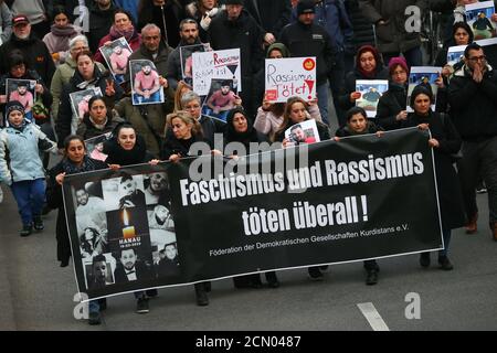 Menschen halten Bilder und ein Transparent mit der Aufschrift "Faschismus und Rassismus töten überall" bereit, als sie an einer Mahnwache für die Opfer einer Schießerei in Hanau bei Frankfurt am 21. Februar 2020 teilnehmen. REUTERS/Kai Pfaffenbach