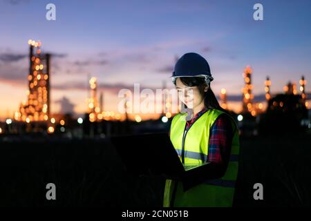 Asiatische Frau petrochemische Ingenieur arbeiten bei Nacht mit Notebook im Inneren Öl-und Gasraffinerie-Anlage Industrie Fabrik in der Nacht für inspector Sicherheit qua Stockfoto